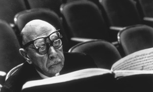 Igor Stravinsky wearing two pairs of glasses while reading musical score during a rehearsal